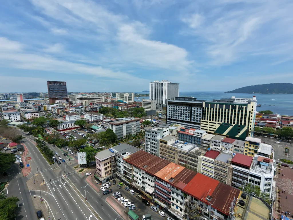 Aerial view of Kota Kinabalu city centre with coastal buildings, busy road, and South China Sea in the background, Sabah, Malaysia